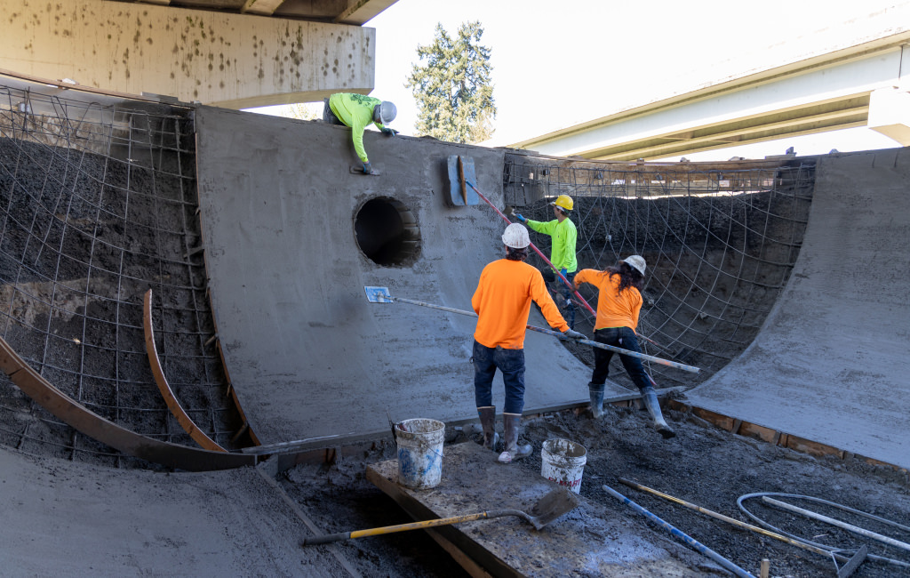 Workers shaping a concrete ramp.