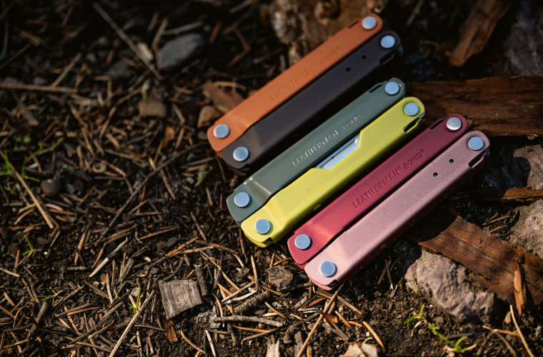 A collection of five differently colored Leatherman Bond tools scattered on the ground, highlighting their diverse hues.