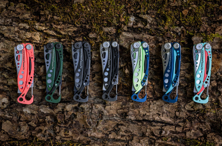 Various Leatherman Skeletools in different colors on a log.