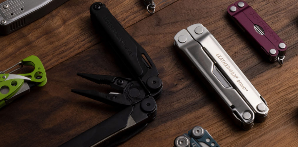 An array of multi-tools on a wooden table.