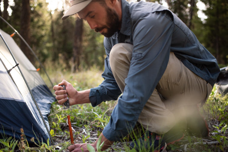 A man pounding a stake in the ground with a Leatherman Signal