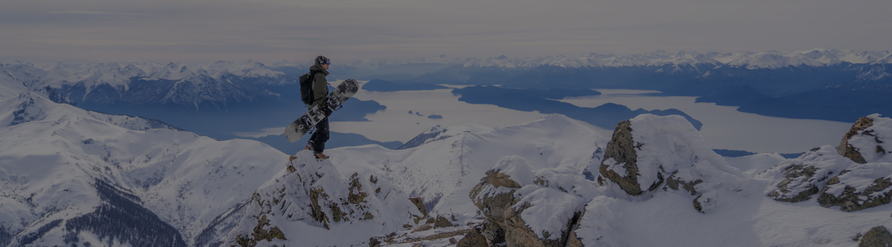 Man with a snowboard on the top of a mountain.