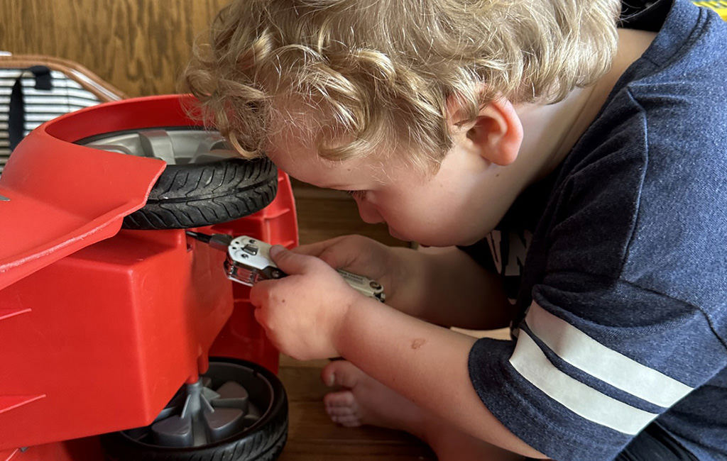 Young boy using Leatherman tool bit driver to fix his car toy.