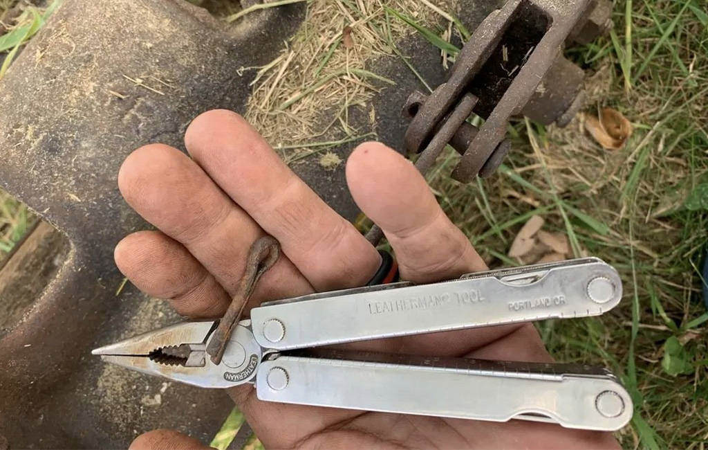 Hand holding 26 year old Leatherman PST to repair a machine.