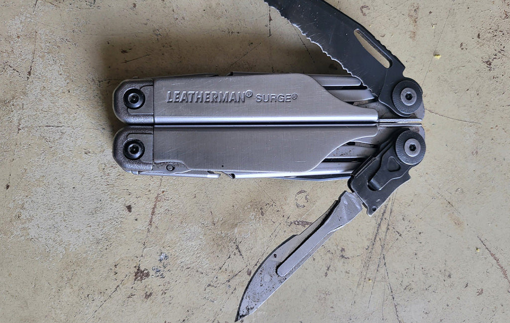 A Leatherman Surge on the working table with knife and serrated knife open.