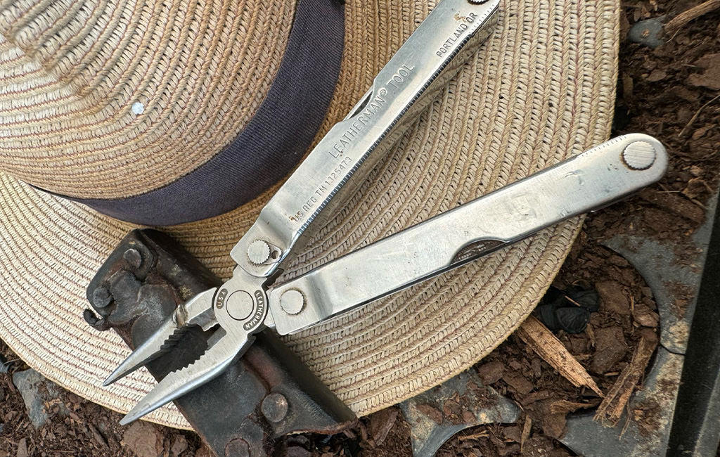 Opened old Leatherman tool and case on top of farm hat.