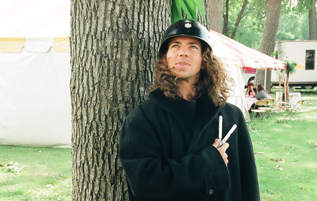 A young man standing in the circus area holding  a Leatheman Tool.